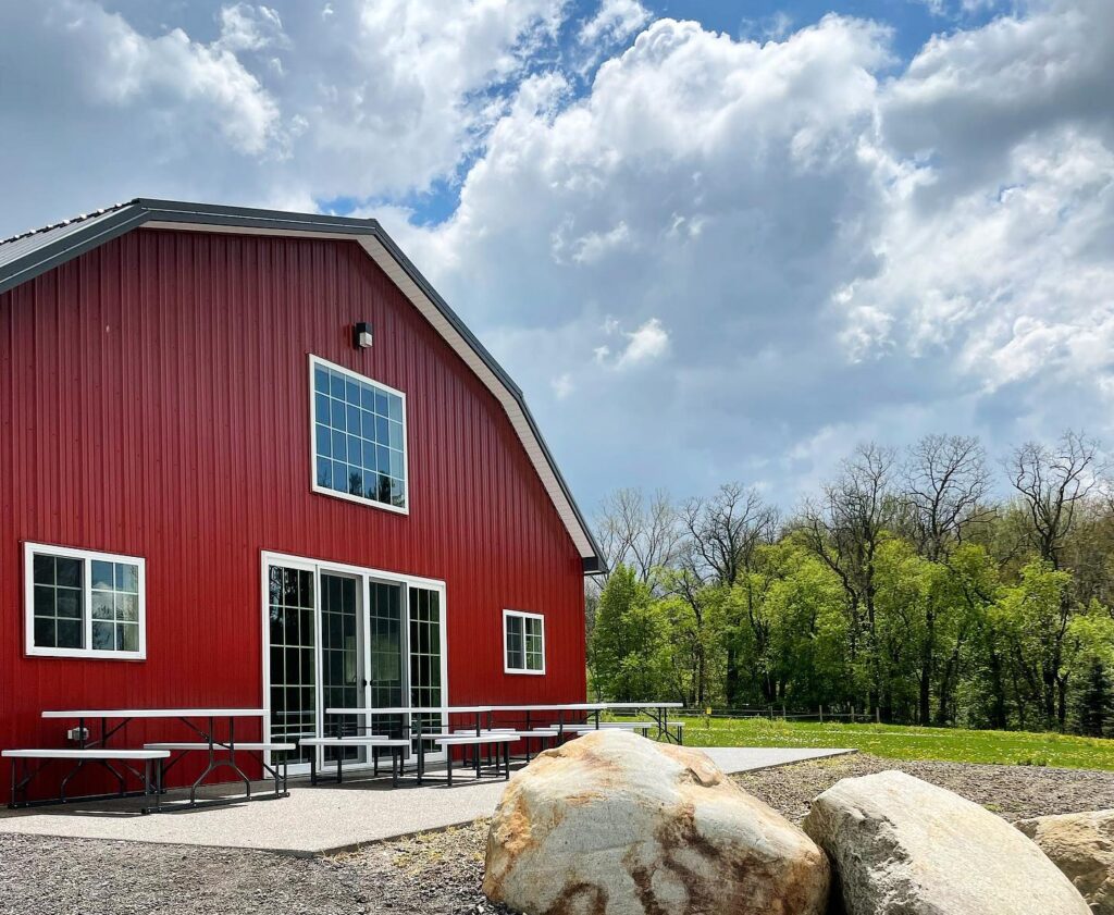 Barn Dog Craft Distilling is found in a red barn with picnic tables outside.